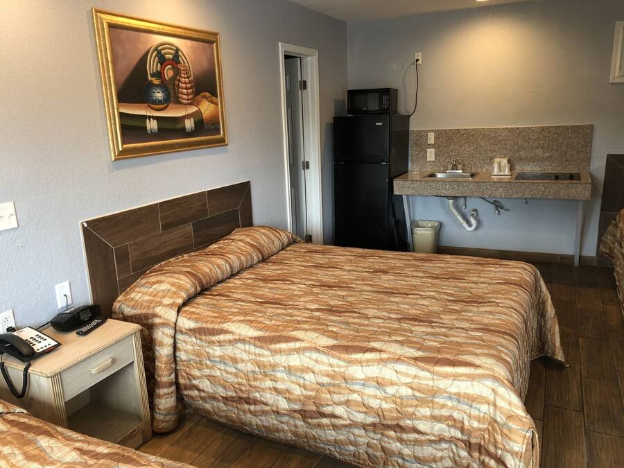 Une chambre d’hôtel équipée d’un lit, d’un bureau avec un téléphone, d’un réfrigérateur, d’un four à micro-ondes et d’une petite kitchenette.