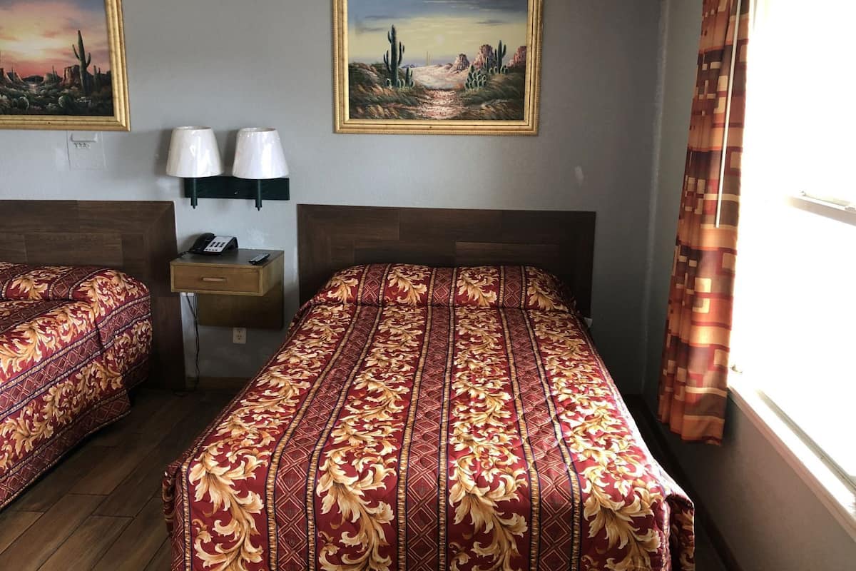 Ein Hotelzimmer mit zwei Betten, einem Nachttisch, einer Lampe und zwei Bildern an der Wand.