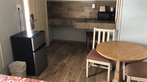 Une cuisine compacte équipée d’un réfrigérateur, d’un four à micro-ondes et d’une petite table à manger avec deux chaises.