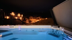 A hot tub area with a control panel and a view of a lit landscape in the background.