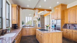 A spacious kitchen with wooden cabinets, granite countertops, and a large island.
