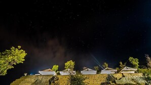 A night view of a hilltop with several white-roofed structures, possibly tents or cabins, with a clear sky above. - Swiss Tent 4 (Dharamshala)