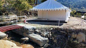A white tent with a peaked roof, set on a stone platform with a metal railing. - Swiss Tent 4 (Dharamshala)
