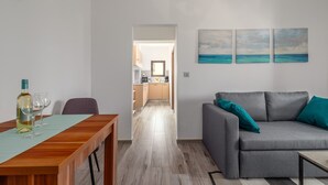 A modern living room with a grey sofa, a wooden dining table, and a kitchen in the background. - Oroz / Apartment Oroz I (Porec)