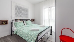 A neatly arranged bedroom with a bed, a bedside table, a small shelf, and a red chair. - Oroz / Apartment Oroz I (Porec)