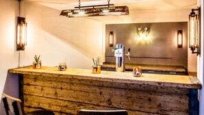 Una zona de bar con mostrador de madera, una máquina de café y dos taburetes.