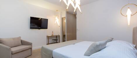 Une chambre à coucher moderne, dotée d’un grand lit, d’un canapé, d’un téléviseur fixé au mur et de luminaires originaux.