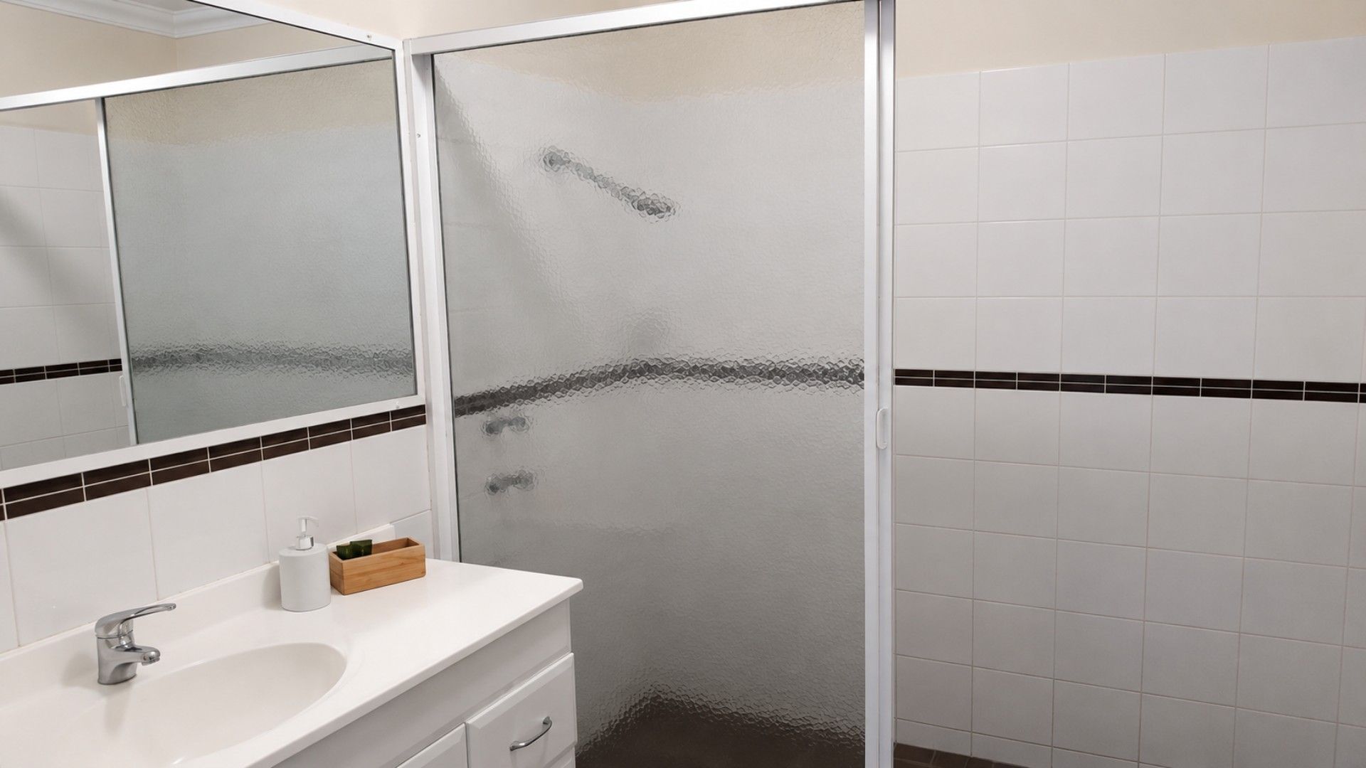 Une salle de bain avec un lavabo blanc, un miroir et une cabine de douche.