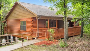 Une cabane en rondins avec un porche, une petite fenêtre et une porte.