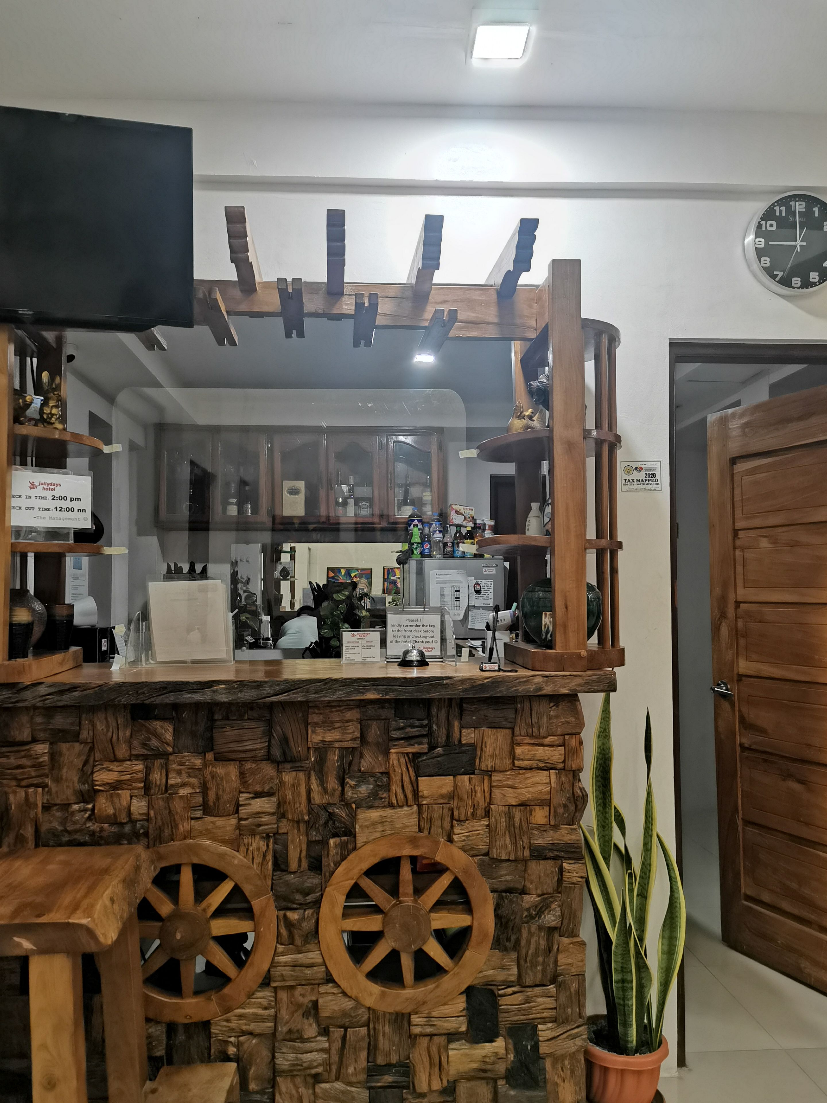 A reception area with a stone counter, wooden wheel decorations, a television above, and a door to the right.