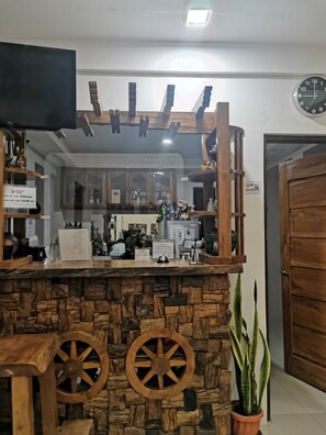 A reception area with a stone counter, wooden wheel decorations, a television above, and a door to the right. - Reddoorz @ Jollydays Hotel Nueva Ecija (San Jose City)