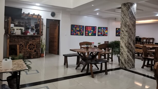 A spacious lobby with a coffee bar, seating area, and artwork on the walls. - Reddoorz @ Jollydays Hotel Nueva Ecija (San Jose City)