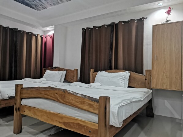 Ein Schlafzimmer mit zwei Holzbetten, weißer Bettwäsche und dunklen Vorhängen.