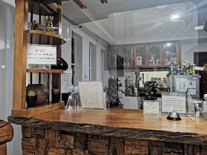Un mostrador de recepción de hotel con una encimera de madera, una vitrina de vidrio y un cartel que indica los horarios de registro de entrada y salida.