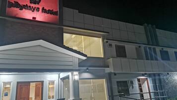 A hotel with a prominent red sign, a glass entrance, and a staircase leading to the entrance.