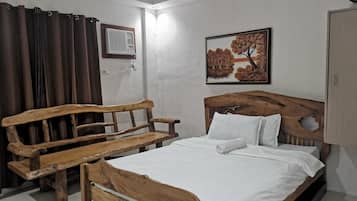 Une chambre à coucher avec un lit en bois, un banc en bois, un climatiseur fixé au mur et un tableau représentant des arbres.