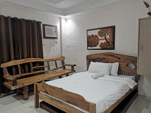 Une chambre à coucher avec un lit en bois, un banc en bois, un climatiseur fixé au mur et un tableau représentant des arbres.