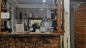 A reception area with a stone counter, wooden wheel decorations, a television, and a clock on the wall. - Reddoorz @ Jollydays Hotel Nueva Ecija (San Jose City)