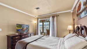 Ein Schlafzimmer mit einem großen Bett, einem Schminktisch, einem Fernseher und einem Bild an der Wand.