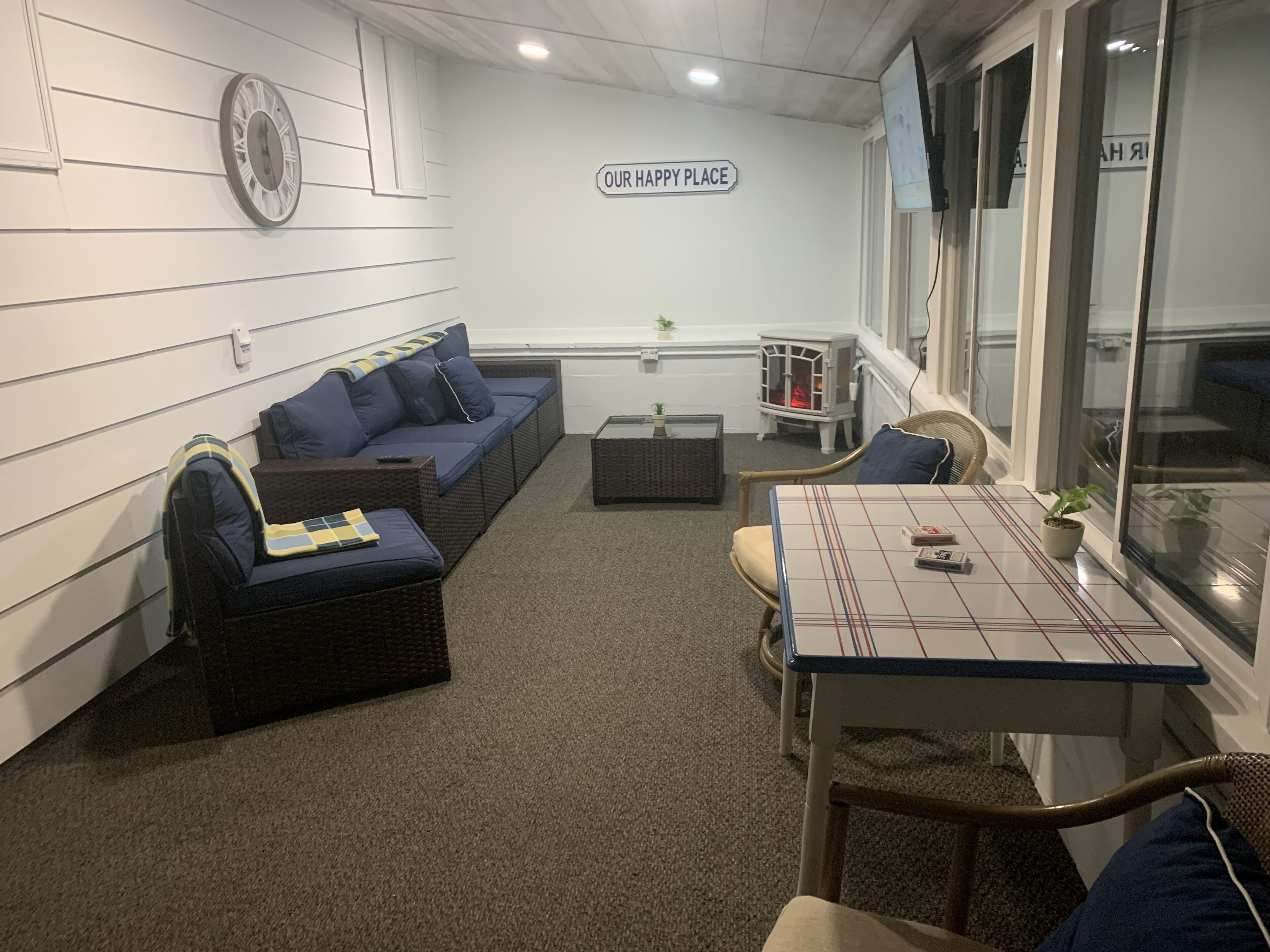 A cozy room with a blue sofa, a small table, and a sign that reads "OUR HAPPY PLACE".