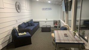Ein gemütliches Zimmer mit einem blauen Sofa, einem kleinen Tisch und einem Schild mit der Aufschrift 'OUR HAPPY PLACE'.