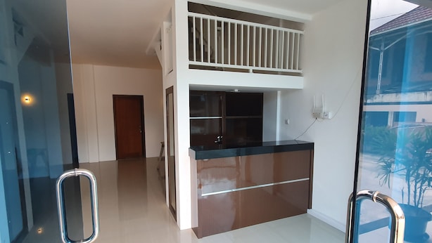 A modern kitchen with a central island, a balcony, and a glass door leading to a balcony with potted plants. - OYO 3816 The Tispa Syariah Residence (Palembang)