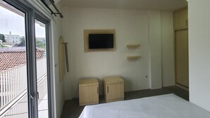 A bedroom with a bed, a television, and two wooden cabinets. - OYO 3816 The Tispa Syariah Residence (Palembang)