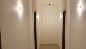 A hallway with white walls and a tiled floor, leading to a door at the end. - OYO 3816 The Tispa Syariah Residence (Palembang)