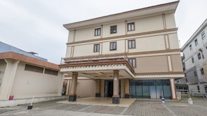 Un hotel a più piani con un ingresso centrale, ampie finestre e una zona esterna coperta.