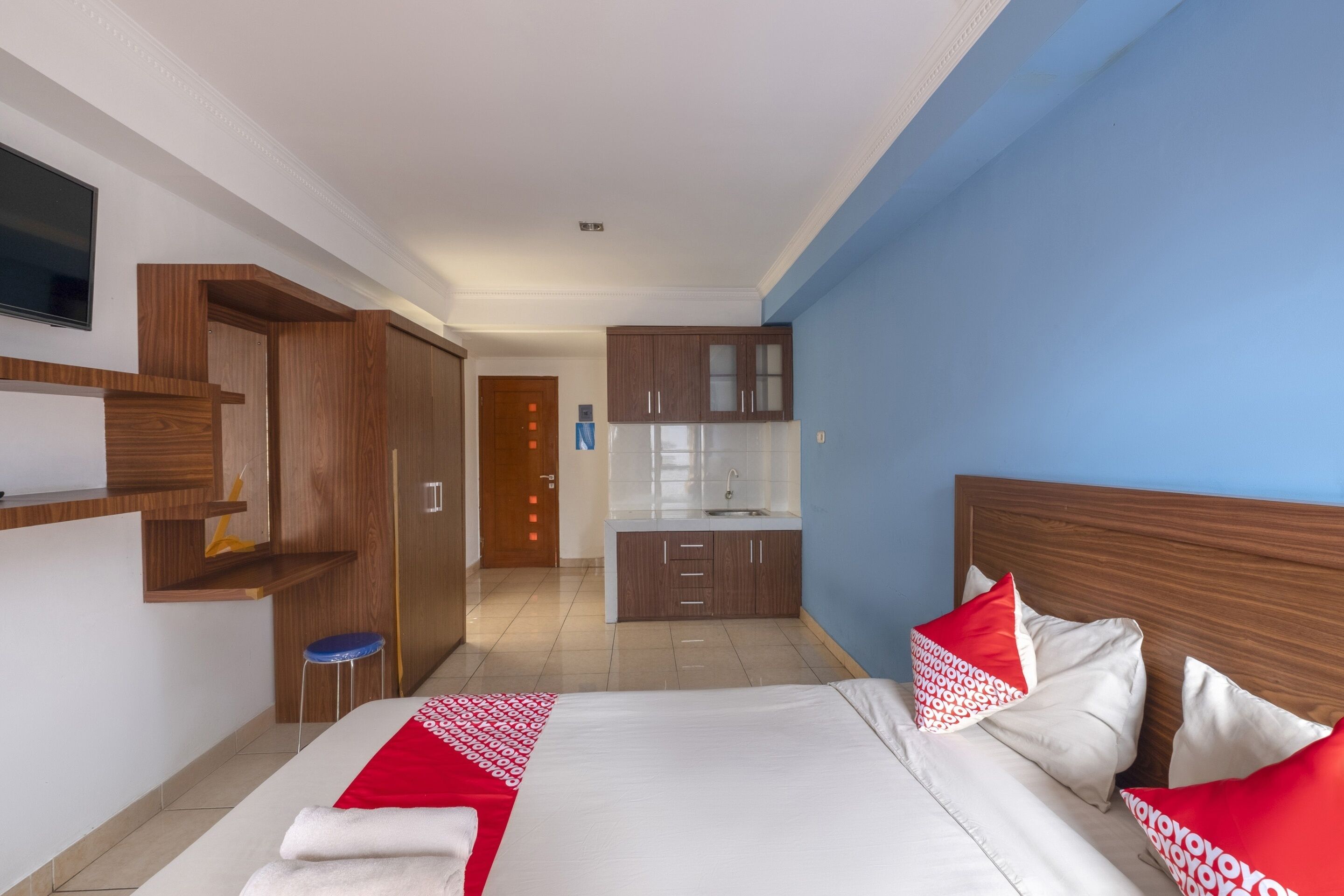 Una habitación de hotel con cama, un escritorio pequeño, kitchenette y baño.