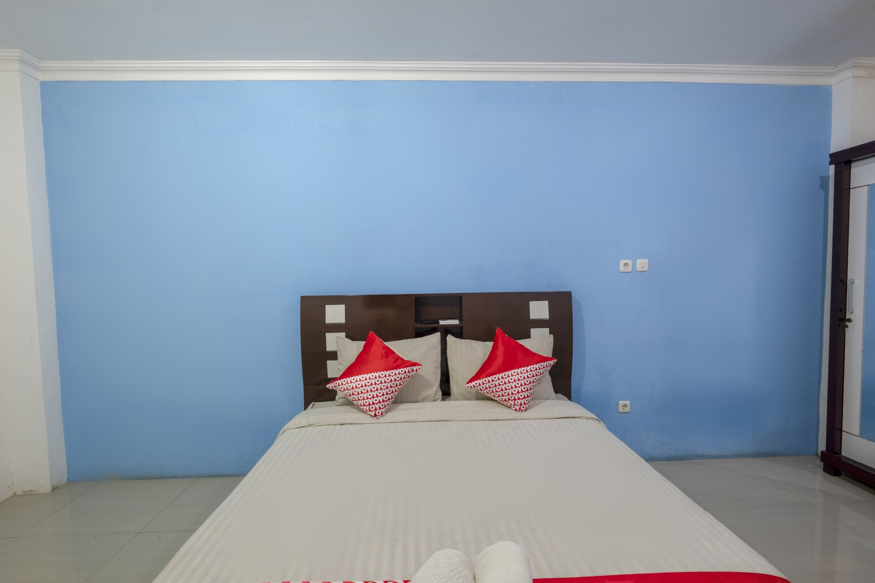 Ein Einzelbett mit Kopfstütze, zwei Kissen und einer weißen Decke in einem Zimmer mit blauen Wänden.