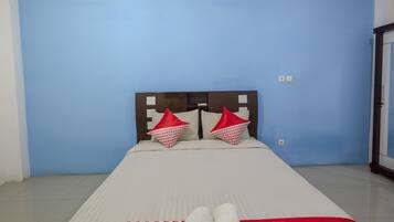 Ein Einzelbett mit Kopfstütze, zwei Kissen und einer weißen Decke in einem Zimmer mit blauen Wänden.