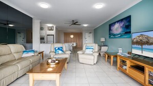 A modern living room with a sofa, two armchairs, a coffee table, and a TV on a wooden stand. - Cote D'Azur 4 Sunshine Beach (Sunshine Beach)