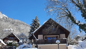 Ein Chalet mit schrägem Dach, Holzfassade und einem Balkon.