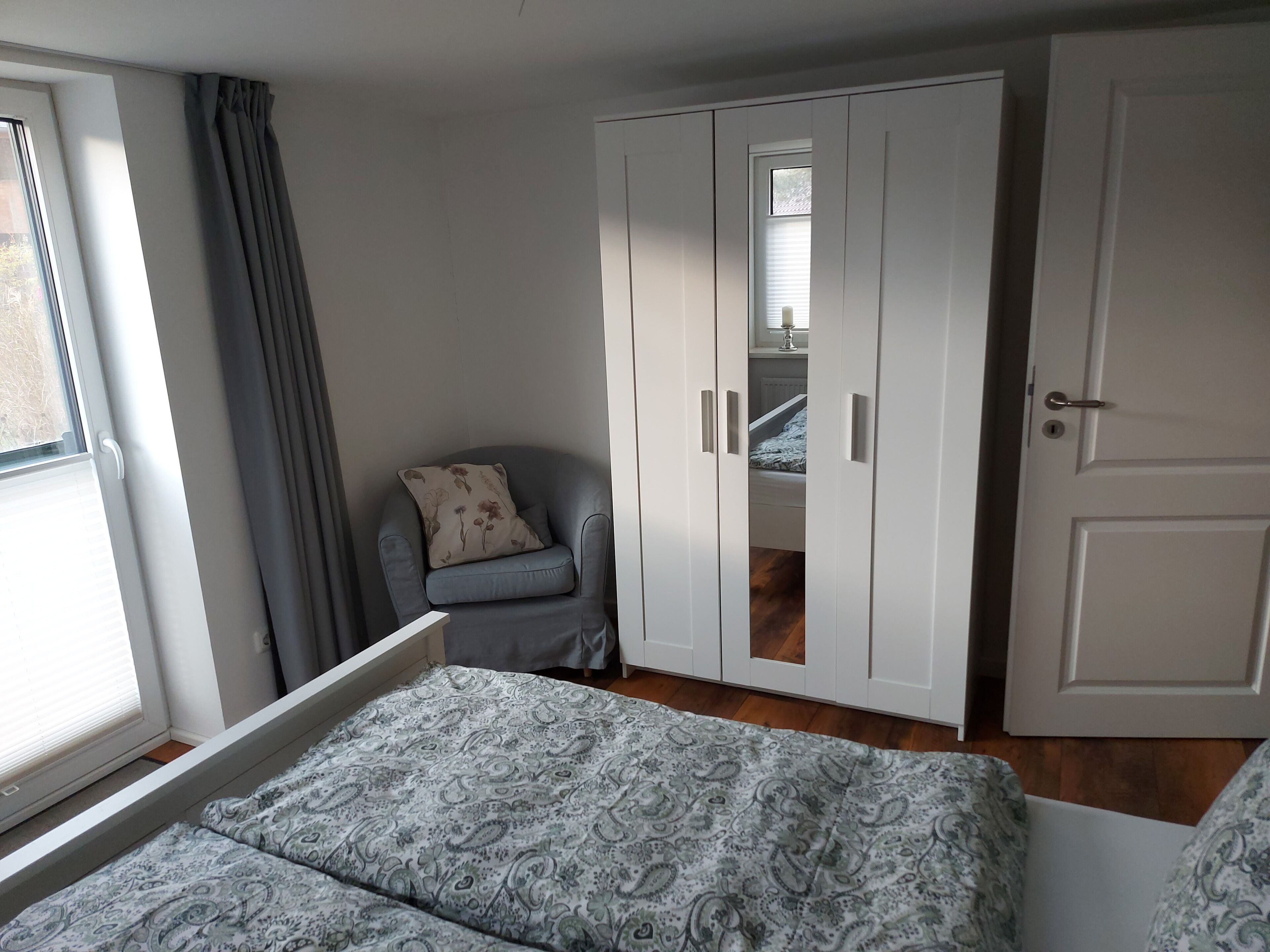 Una camera da letto con un letto, una sedia, un armadio e una finestra.