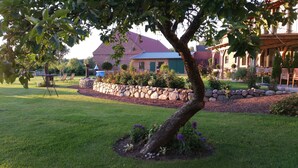 Un jardin bien entretenu, agrémenté d’un mur en pierre, d’un arbre et d’un espace patio avec des meubles d’extérieur.