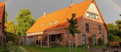 A two-story house with a red roof, a covered porch, and a brick exterior.