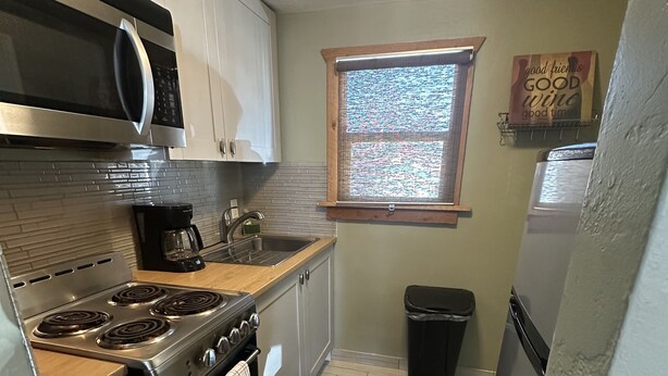 A compact kitchen with a gas stove, oven, microwave, and a coffee maker. - Beautiful Studio Suite (Loa)