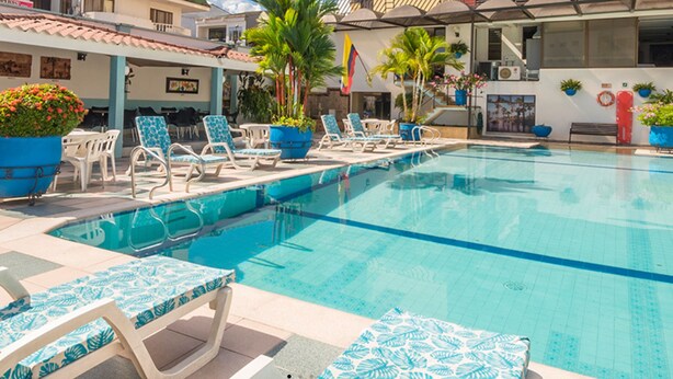 A swimming pool with lounge chairs and potted plants. - Hotel Don Lolo (Villavicencio)