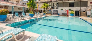 A swimming pool with lounge chairs and potted plants. - Hotel Don Lolo (Villavicencio)