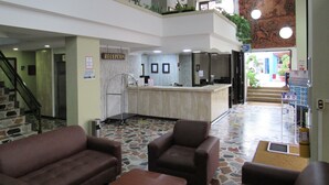 A lobby with a reception desk, two brown sofas, a staircase, and a terrazzo floor. - Hotel Don Lolo (Villavicencio)