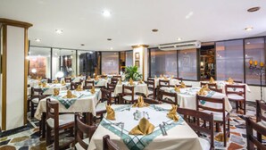 A restaurant with multiple tables set for dining, each with a tablecloth and napkin. - Hotel Don Lolo (Villavicencio)
