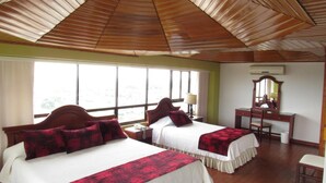 A hotel room with two beds, a desk, a chair, and a large window. - Hotel Don Lolo (Villavicencio)