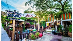 A rustic outdoor setting with a pizza oven and a garden sign.
