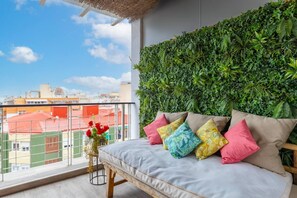 A balcony with a sofa, pillows, and a wall of greenery. - Fidalsa Penthouse Amazing View (Alicante)