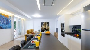 A modern kitchen with a long dining table, a sofa, and artwork on the walls. - Fidalsa Penthouse Amazing View (Alicante)