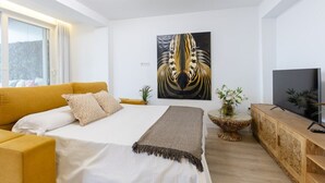 A modern bedroom with a large bed, a sofa, a TV, and a painting on the wall. - Fidalsa Penthouse Amazing View (Alicante)