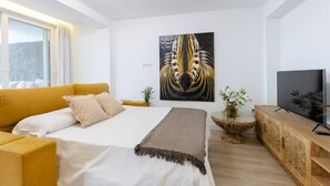 A modern bedroom with a bed, a sofa, a TV, and a wall art piece. - Fidalsa Penthouse Amazing View (Alicante)