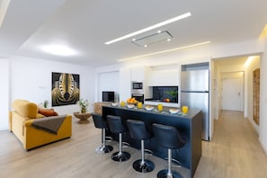 Een moderne keuken met een centraal eiland, barstoelen, een bank en een eettafel.