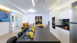 A modern kitchen with a dining area, a large painting, and a sofa. - Fidalsa Penthouse Amazing View (Alicante)
